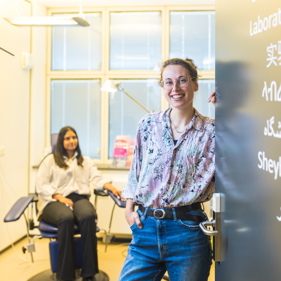 Een collega van GGD Fryslân verwelkomt je in een behandelkamer, met op de achtergrond een cliënt.