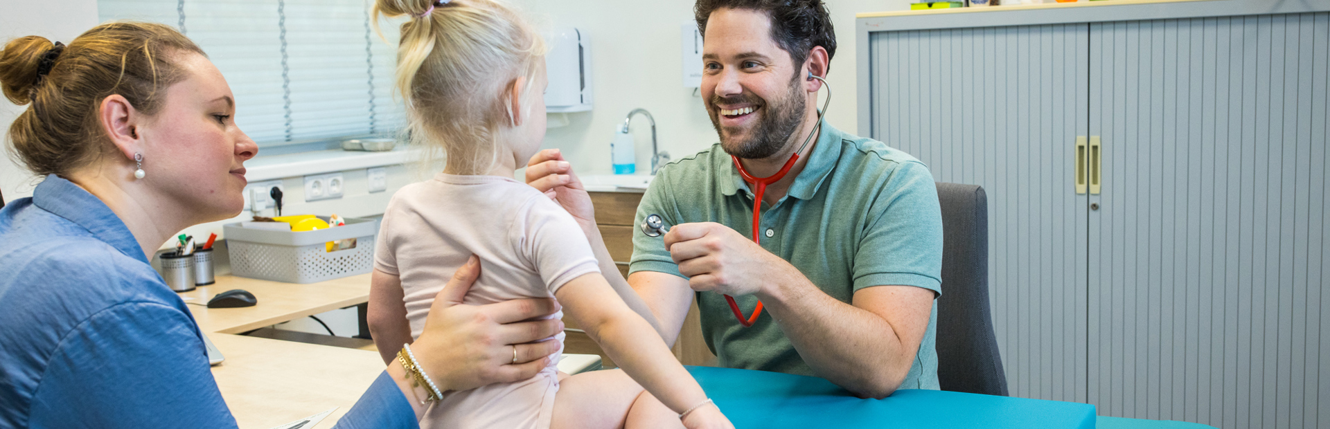 Jeugdarts Onderzoekt Lachend Kind En Moeder Houdt Haar Vast